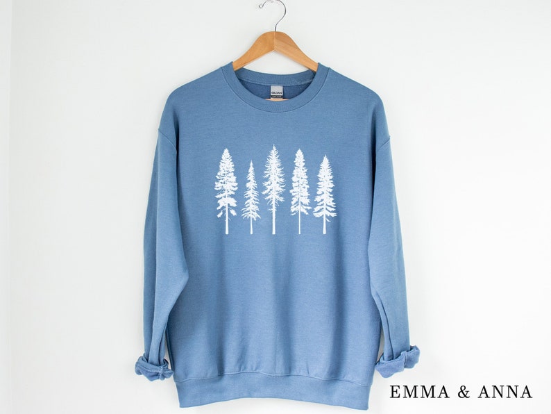 May include: A blue sweatshirt with a white graphic of five pine trees. The trees are silhouetted against a light blue background.