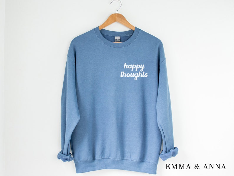 May include: A light blue sweatshirt with the text "happy thoughts" printed in white on the front.