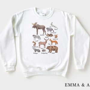 May include: White sweatshirt with a graphic of various woodland animals, including a moose, wolf, deer, fox, squirrel, raccoon, bear, badger, hedgehog, and chipmunk. Each animal is labeled with its name.