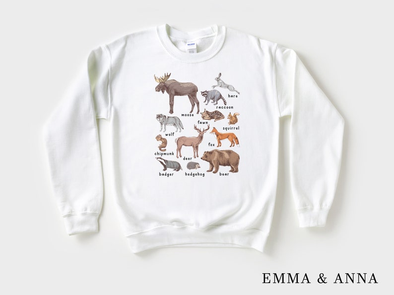 May include: White sweatshirt with a graphic of various woodland animals, including a moose, wolf, deer, fox, squirrel, raccoon, bear, badger, hedgehog, and chipmunk. Each animal is labeled with its name.
