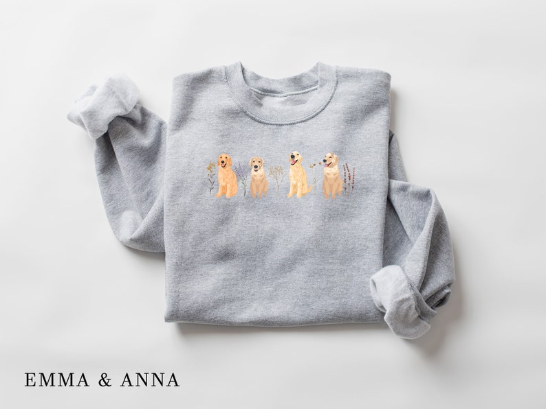 May include: Gray sweatshirt with a print of four golden retriever dogs sitting in a row with flowers and grass behind them.