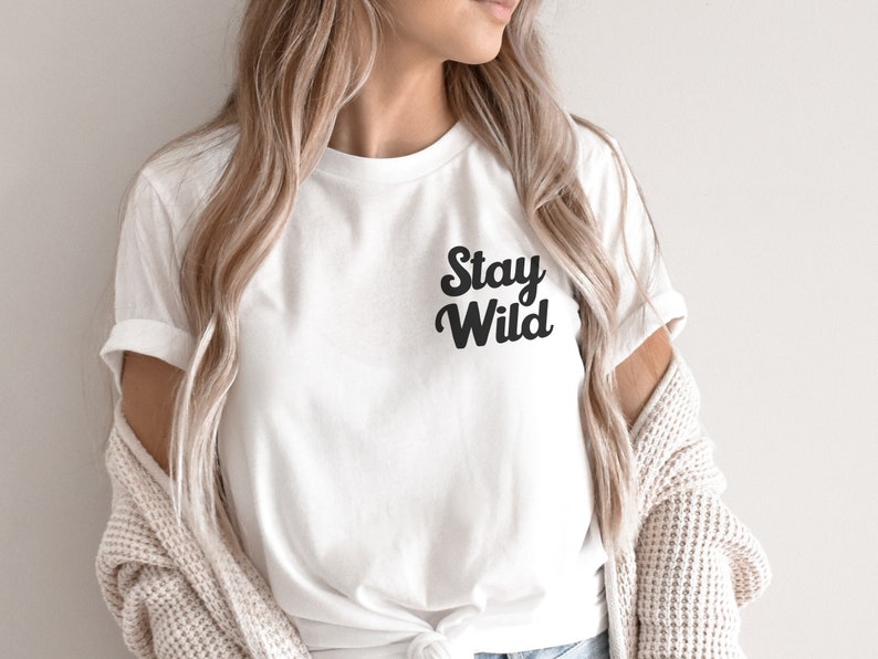 May include: White t-shirt with black text that reads "Stay Wild" in a retro font.