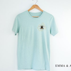 May include: A light blue t-shirt with a bee and honeycomb design embroidered on the front.