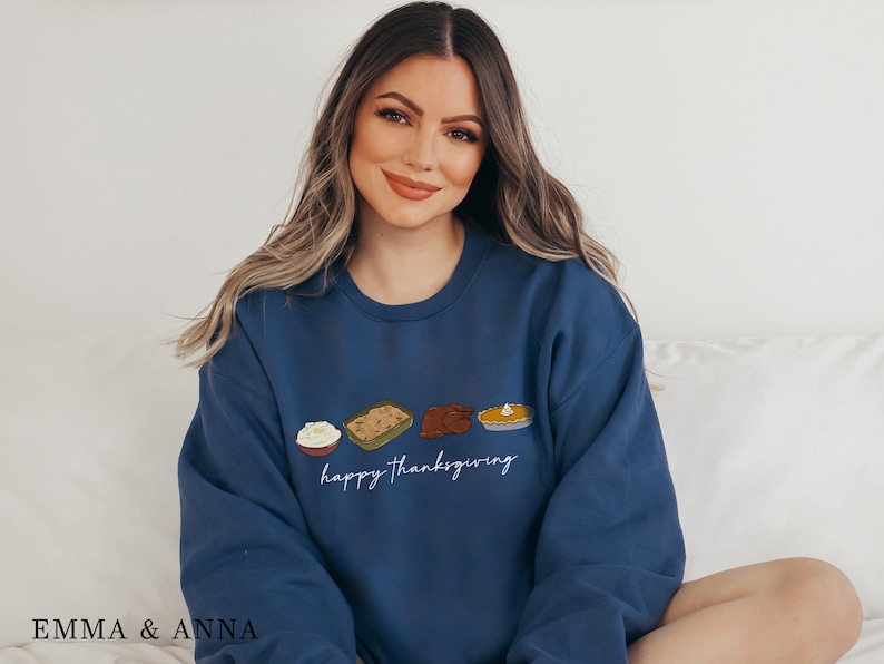 K&ouml;nnte beinhalten: Ein marineblauer Pullover mit einer wei&szlig;en Grafik von Thanksgiving-Lebensmitteln und dem Text "happy thanksgiving".