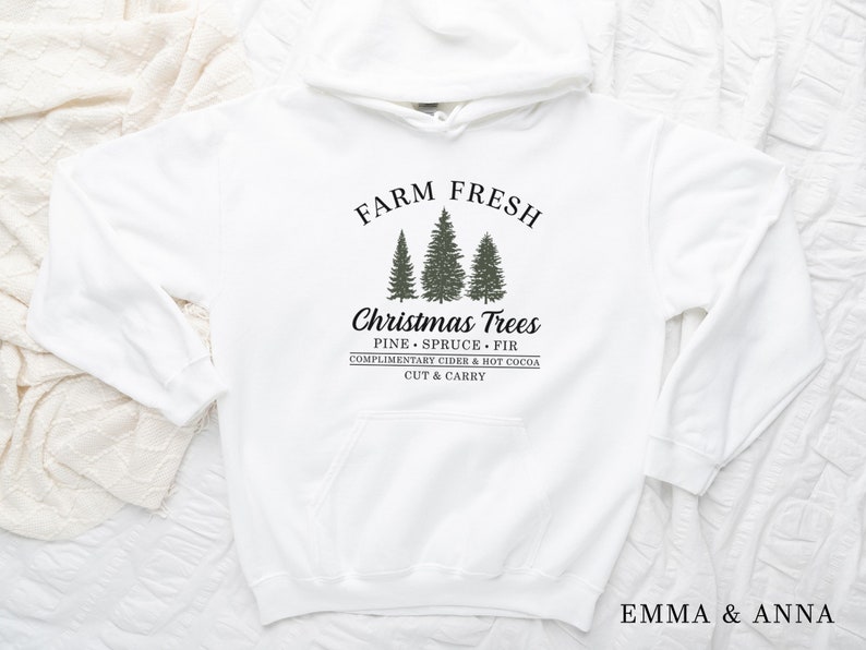 May include: White hoodie with a black graphic that says "Farm Fresh Christmas Trees" with a drawing of three evergreen trees and the text "Pine Spruce Fir Complimentary Cider & Hot Cocoa Cut & Carry".