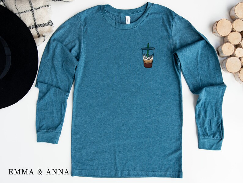 Peut inclure: Un t-shirt &agrave; manches longues bleu sarcelle avec un petit graphique d'un caf&eacute; glac&eacute; sur la poitrine gauche.