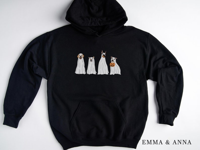 May include: Black hoodie featuring a graphic of four dogs dressed as ghosts. The dogs are wearing white sheets with their heads poking out. The text "EMMA & ANNA" is printed on the bottom right corner of the hoodie.