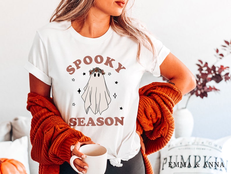 May include: White t-shirt with a ghost wearing a floral crown and the text "Spooky Season" in brown letters.