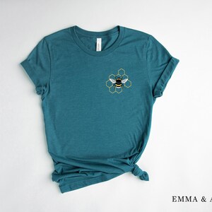 May include: Teal blue t-shirt with a yellow and black bee graphic in a honeycomb design.