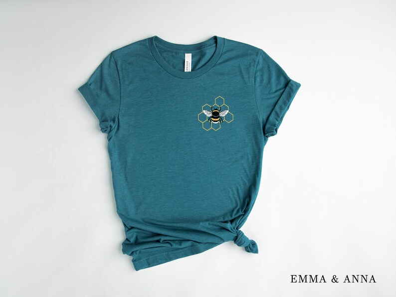 May include: Teal blue t-shirt with a yellow and black bee graphic in a honeycomb design.
