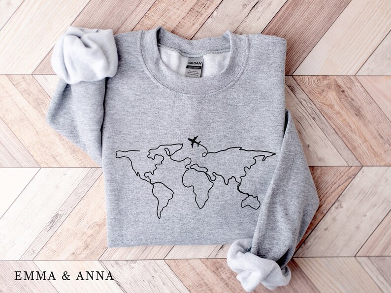 May include: Gray sweatshirt with a black outline of the world and a small airplane flying over it.