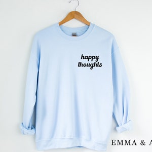 May include: A light blue sweatshirt with the text "happy thoughts" printed in black on the front.