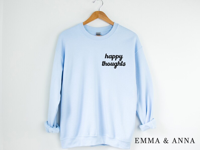 May include: A light blue sweatshirt with the text "happy thoughts" printed in black on the front.