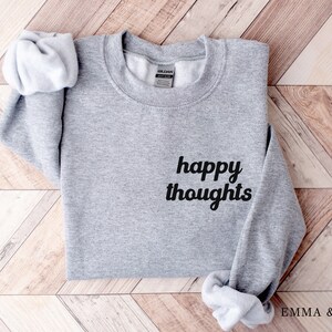 May include: Gray sweatshirt with the text "happy thoughts" in black cursive lettering.