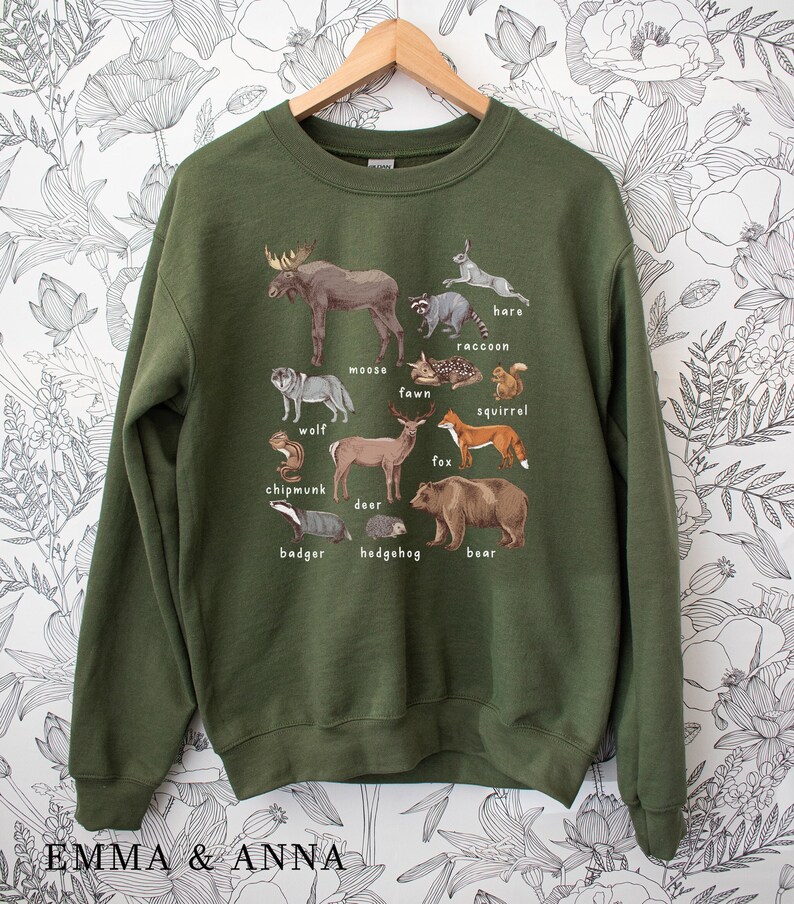 May include: Green sweatshirt with a graphic print of various forest animals, including a moose, deer, fox, squirrel, and bear. The animals are labeled with their names.
