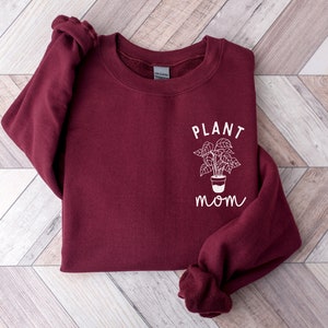May include: Burgundy sweatshirt with a white graphic of a potted plant and the text "PLANT MOM".
