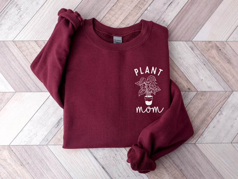 May include: Burgundy sweatshirt with a white graphic of a potted plant and the text "PLANT MOM".