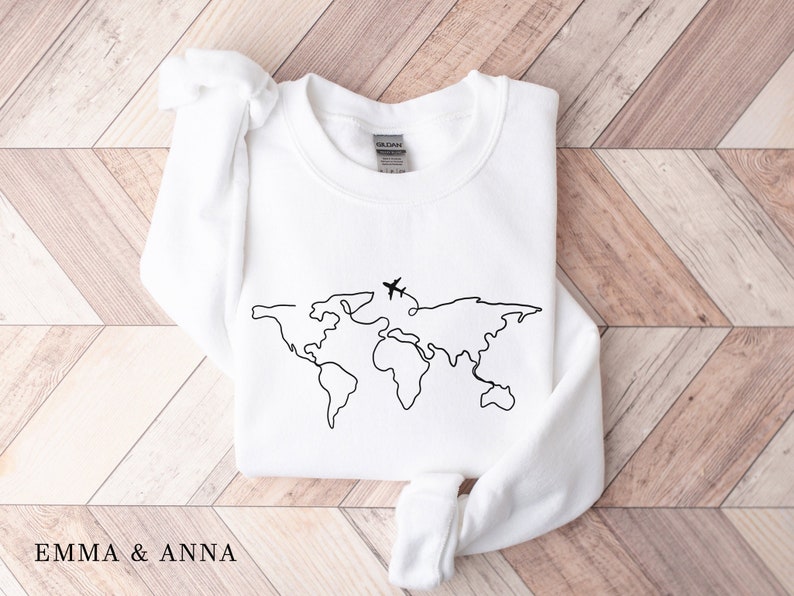 May include: White sweatshirt with a black outline of the world map and a small airplane above it.