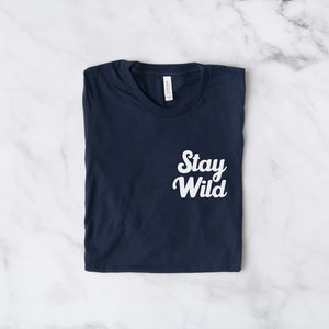 May include: A navy blue t-shirt with the text "Stay Wild" printed in white on the front.