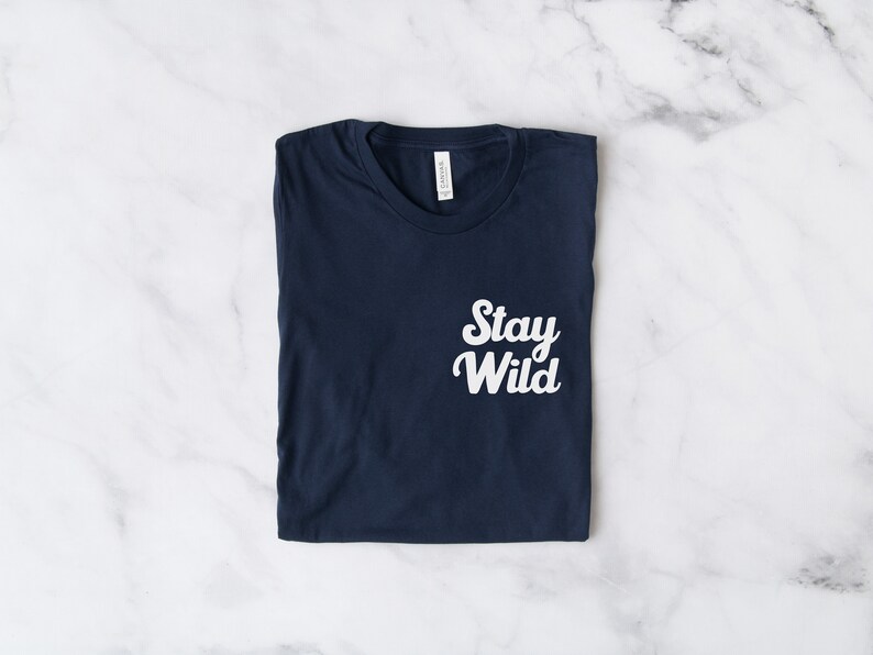 May include: A navy blue t-shirt with the text "Stay Wild" printed in white on the front.