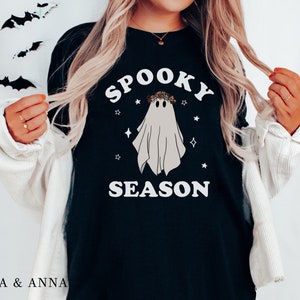 May include: Black t-shirt with a white ghost wearing a floral crown and the text "Spooky Season" in white letters.