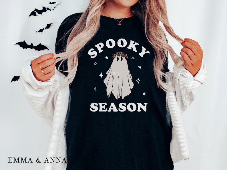 May include: Black t-shirt with a white ghost wearing a floral crown and the text "Spooky Season" in white letters.