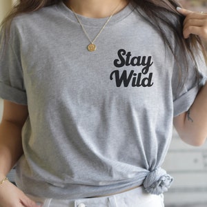 May include: A gray t-shirt with the text "Stay Wild" in black, stylized lettering.