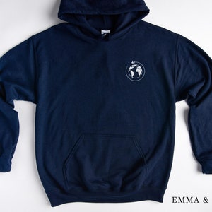 May include: A navy blue hoodie with a white globe and airplane graphic on the left chest. The hoodie has a kangaroo pocket and a drawstring hood.