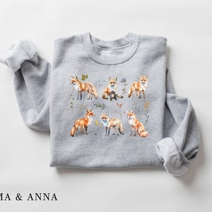 May include: A gray sweatshirt with a print of multiple orange foxes surrounded by flowers and leaves.