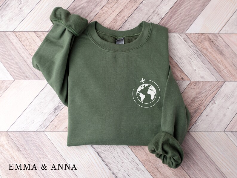 May include: A green sweatshirt with a white graphic of a globe with airplanes flying around it.