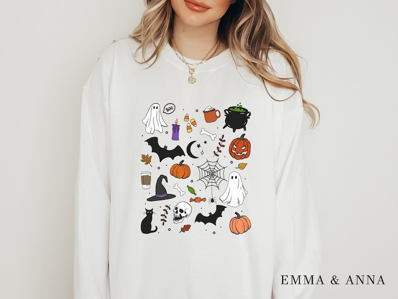 May include: White sweatshirt with a black and white illustration of various Halloween themed items including a ghost, a bat, a witch's hat, a pumpkin, a cauldron, a spider web, and a skull.