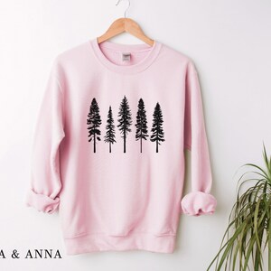 May include: A pink sweatshirt with a black silhouette of five pine trees on the front.