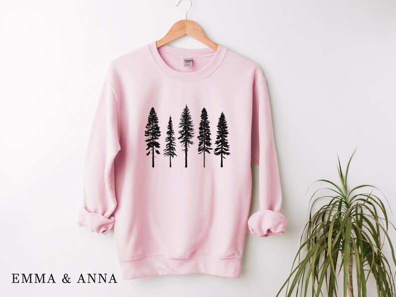 May include: A pink sweatshirt with a black silhouette of five pine trees on the front.