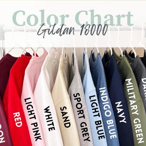 May include: Color chart for Gildan 18000 sweatshirts, showing 11 different colors: maroon, red, light pink, white, sand, sport grey, light blue, indigo blue, navy, military green, dark heather, and black.