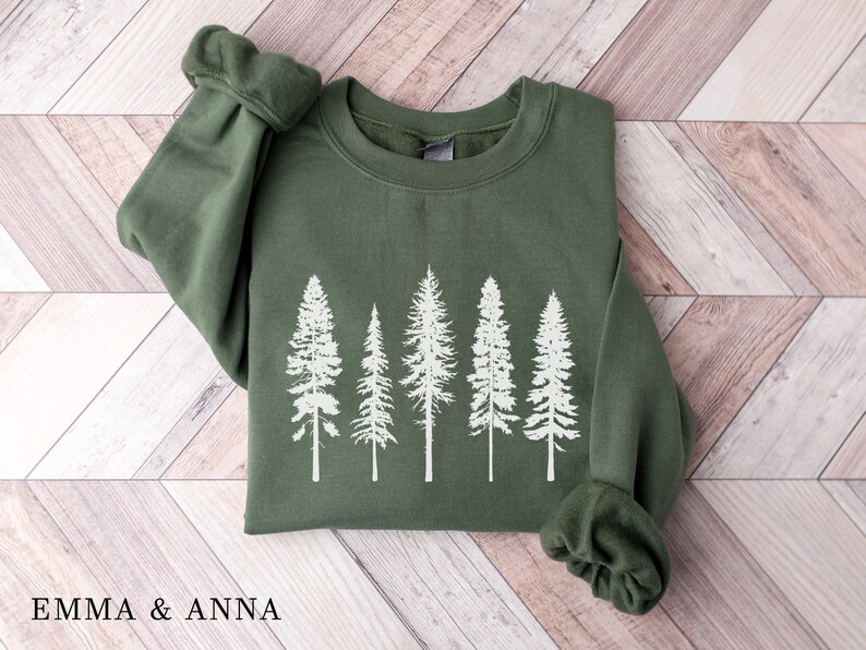 May include: A green sweatshirt with a white silhouette of five pine trees printed on the front.