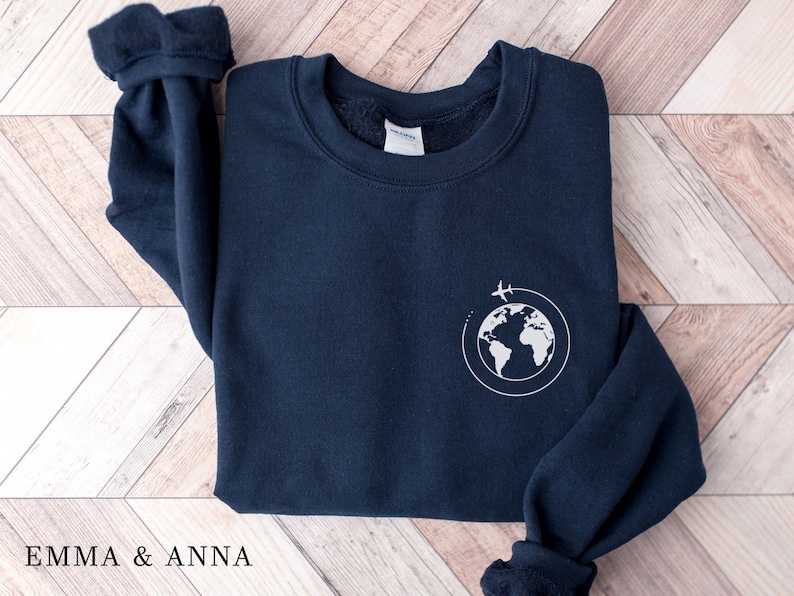 May include: A navy blue sweatshirt with a white graphic of a globe with airplanes flying around it.