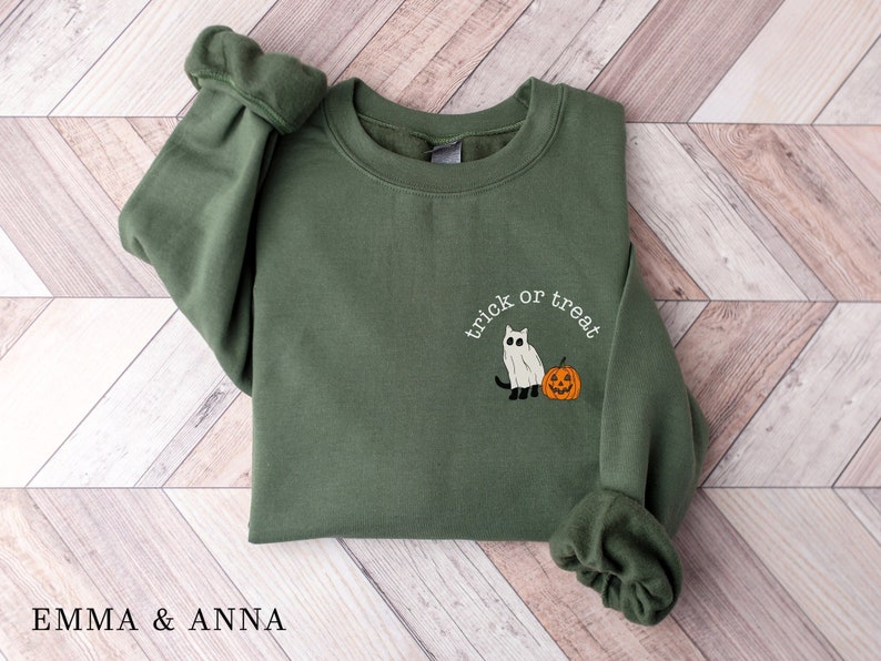 May include: A green sweatshirt with a white ghost and orange pumpkin graphic and the text "trick or treat" on the front.