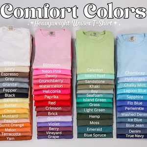 May include: A display of 24 different colored t-shirts stacked in rows of four. The t-shirts are all the same style, a heavyweight unisex t-shirt. The colors are arranged in three columns, with each column representing a different color family: white, pink, green, blue. The colors are labeled with their names, such as "White", "Ivory", "Espresso", "Gray", "Granite", "Pepper", "Black", "Banana", "Butter", "Citrus", "Mustard", "Peachy", "Burnt Orange", "Melon", "Terracotta", "Yam", "Blossom", "Neon Pink", "Peony", "Crunchberry", "Watermelon", "Heliconia", "Paprika", "Red", "Crimson", "Brick", "Orchid", "Violet", "Berry", "Vineyard", "Grape", "Celedon", "Island Reef", "Sandstone", "Khaki", "Bay", "Seafoam", "Island Green", "Grass", "Light Green", "Hemp", "Moss", "Emerald", "Blue Spruce", "Chambray", "Hydrangea", "Chalky Mint", "Lagoon Blue", "Sapphire", "Flo Blue", "Periwinkle", "Washed Denim", "Ice Blue", "Blue Jean", "Denim", "True Navy".