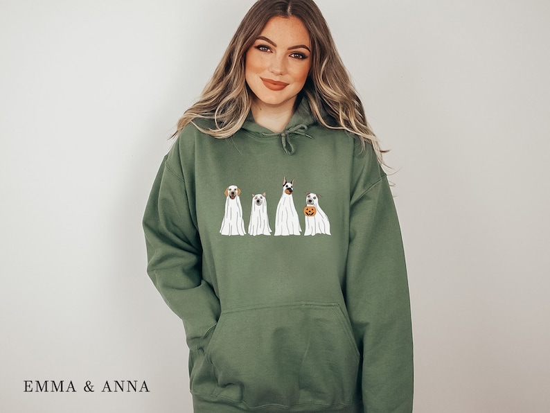May include: A green hooded sweatshirt featuring a graphic of four dogs dressed as ghosts. The dogs are wearing white sheets with their heads poking out. One dog is holding a pumpkin.