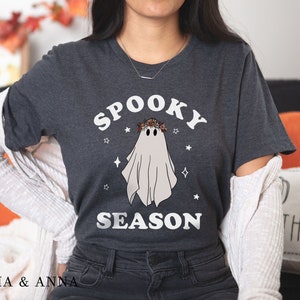 May include: A dark gray t-shirt with a white ghost wearing a floral crown and the text "Spooky Season".