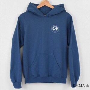 May include: A blue hooded sweatshirt with a white graphic of a globe with a plane flying over it.
