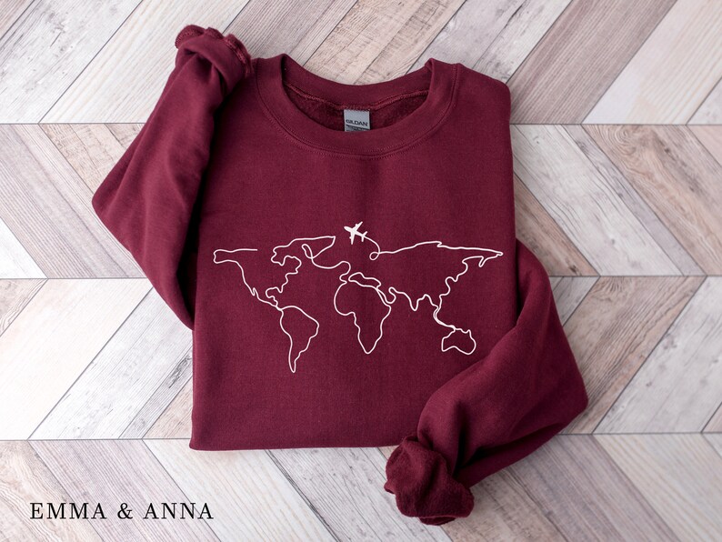 May include: Burgundy sweatshirt with a white outline of the world map and a small airplane graphic.