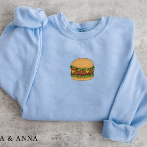 May include: A light blue sweatshirt with a cartoon image of a hamburger on the front.
