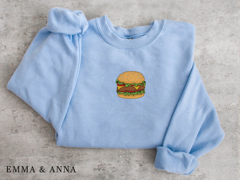 May include: A light blue sweatshirt with a cartoon image of a hamburger on the front.