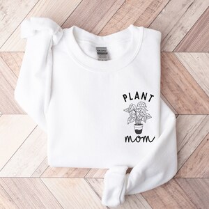 May include: White sweatshirt with the text "PLANT mom" and a simple line drawing of a potted plant.
