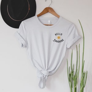 May include: A light gray t-shirt with a graphic of a sun and the text "Hello Sunshine" on the front.
