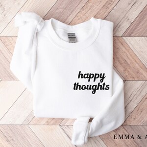 May include: White sweatshirt with the text "happy thoughts" in black cursive lettering.