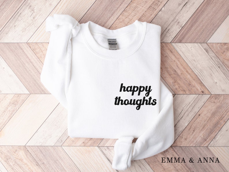 May include: White sweatshirt with the text "happy thoughts" in black cursive lettering.