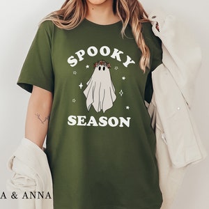 May include: A green t-shirt with a white ghost wearing a flower crown and the text "Spooky Season" in white.