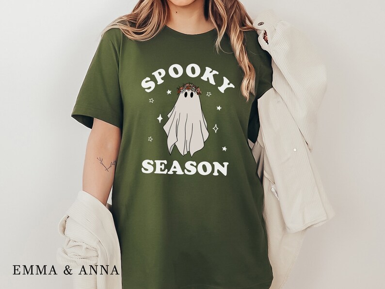 May include: A green t-shirt with a white ghost wearing a flower crown and the text "Spooky Season" in white.